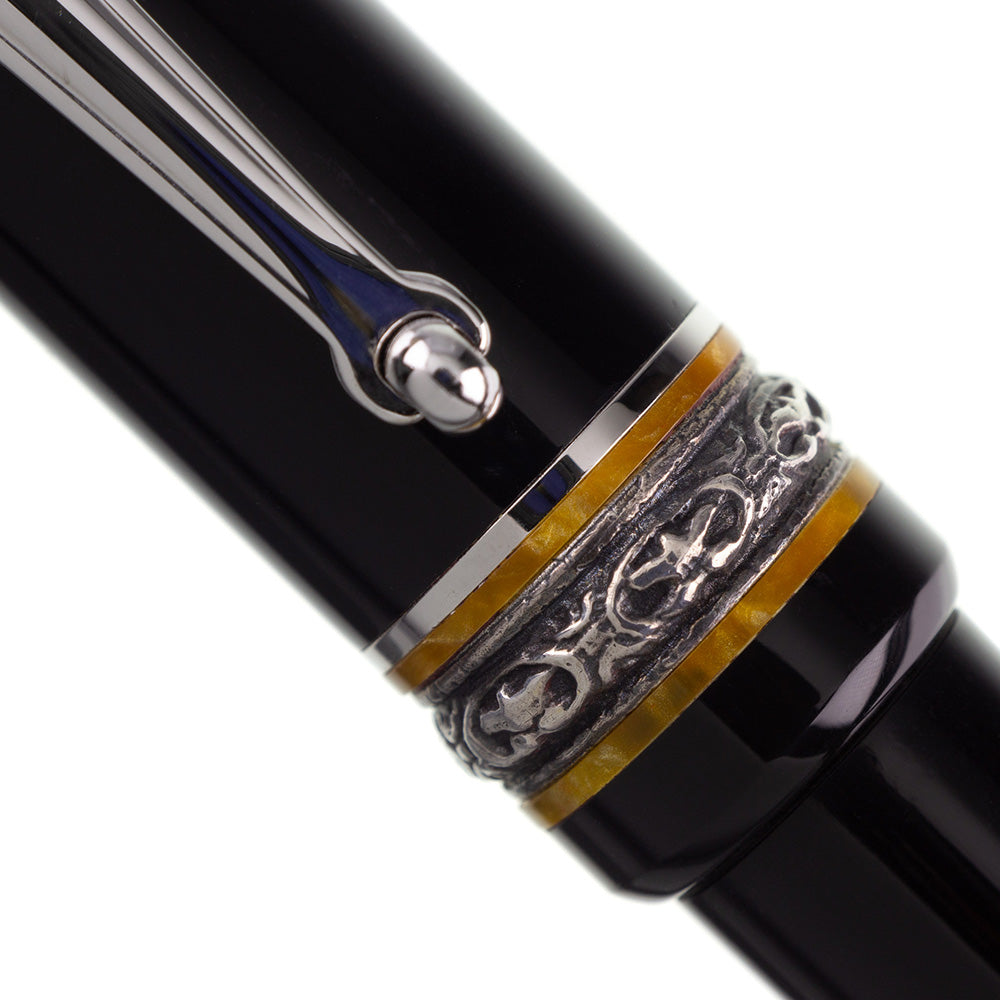 Delta Dolcevita Soriee Media Black Resin with Sterling Silver Trim Ballpoint Pen This Delta Dolce Vita Soiree ballpoint pen exudes classic Italian style, with accenting bands of amber-orange pearlescent celluloid, and finely engraved sterling silver trim. Colour : Black Clip: Platinum plated elastic alloy with rolling wheel to facilitate sliding. Cap & Body: Intense black color Trim: Sterling silver and amber-orange acrylic resin. Central ring engraved in ancient Pompeian motif. Packaging: Elegant case